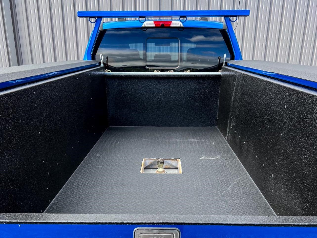 Blue truck with ArmorThane spray on truck bed liner and hitch